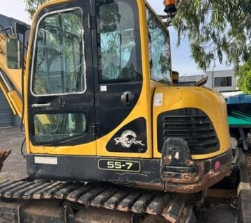Yellow and black mini excavator with tracked wheels at a machinery yard. - For Sale