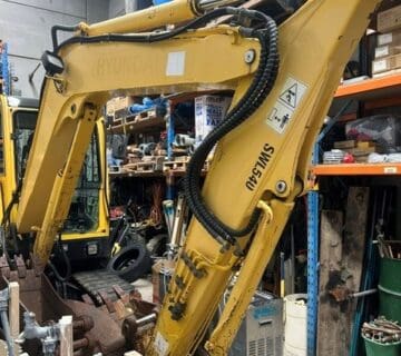 Yellow Hyundai excavator in a warehouse with tools and equipment. - For Sale
