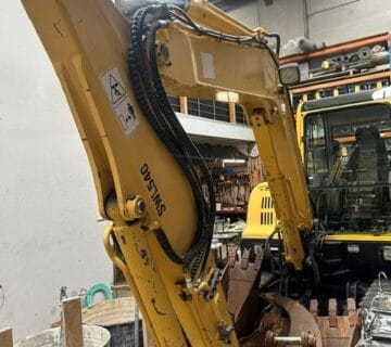 Yellow excavator with hydraulic arm in industrial warehouse. - For Sale
