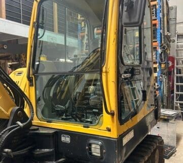 Yellow mini excavator in warehouse for sale, compact construction equipment. - For Sale