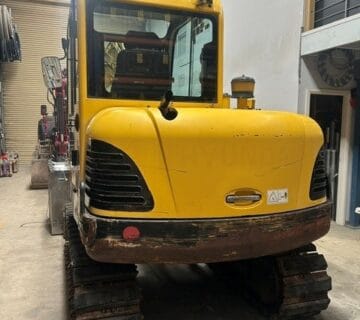 Yellow compact excavator with tracked wheels inside warehouse. - For Sale