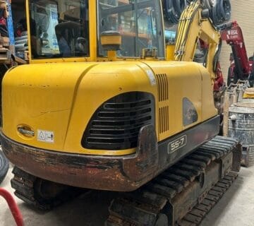 Yellow Komatsu mini excavator with tracked undercarriage in warehouse. - For Sale